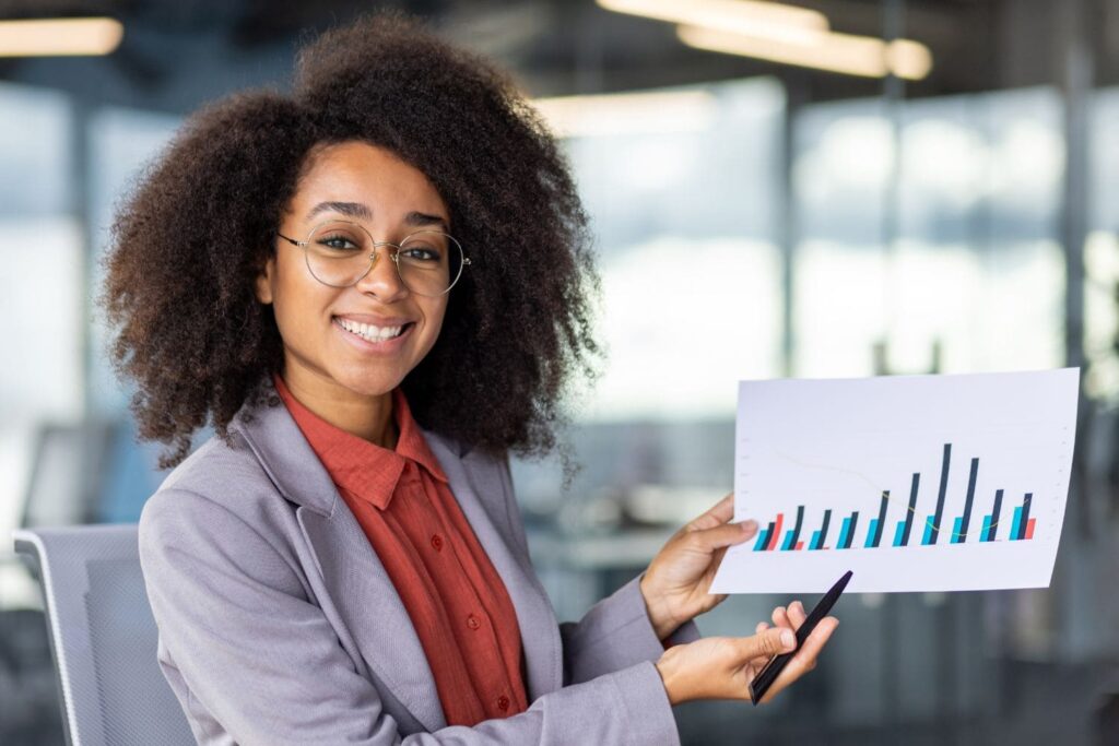 Foto de mulher segurando folha impressa com gráfico, fazendo menção à análise.